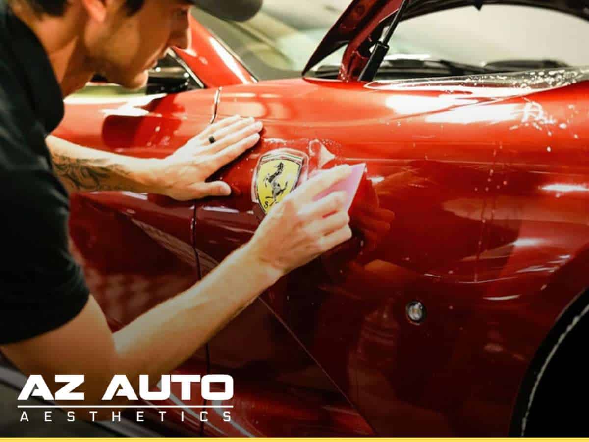 Technician applying XPEL Paint Protection film to red sports car